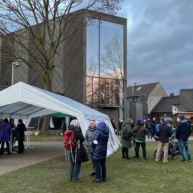 Unterschiedliche Menschen auf der Wiese vor der Immanuel-Kirche