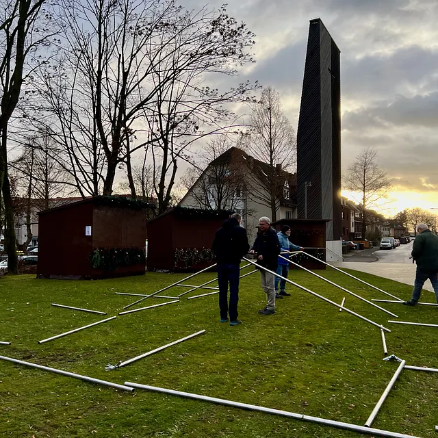 Mehrere Personen bauen Stangen für ein großes Zelt zusammen