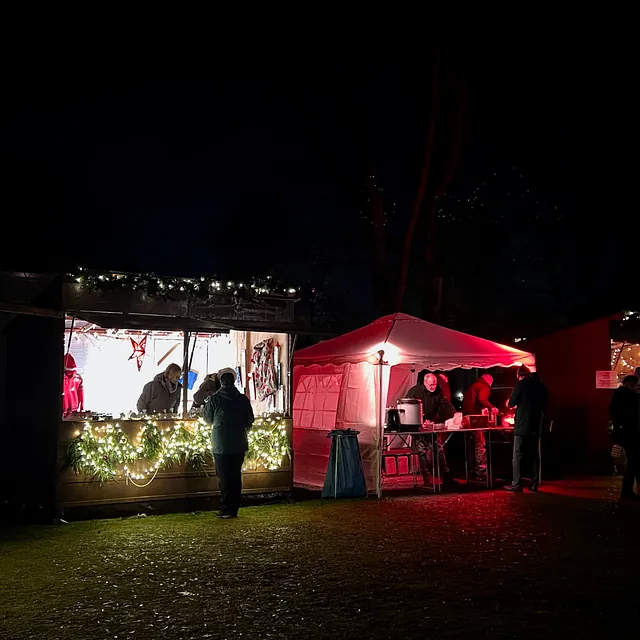 Vor den erleuchteten Bude tummeln sich im Dunkeln nur noch wenige Besucher:innen