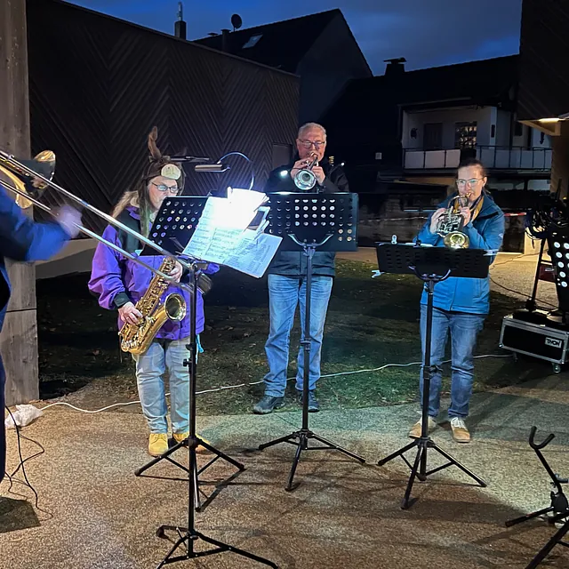 Ein Bläserquintett spielt bei Dunkelheit vor der Immanuel-Kirche: 2 Trompeten, 1 Posaune, 2 Saxofone