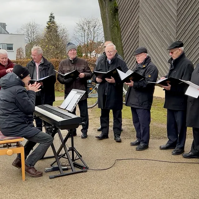 Ein Männerchor vor der Immanuel-Kirche, bei Tag